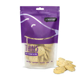 A package of 'THINS Fish, Coconut & Dill' dog treats from The Treatery, showing the product name and some treats outside the package.