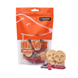 A bag of Treatery Halloween Candy Skulls dog treats on a white background, with two skull-shaped treats and several small candy treats displayed in front of the packaging.
